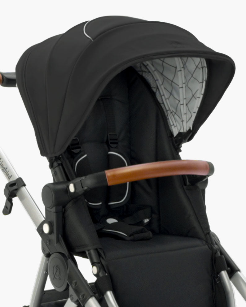 Close-up of a modern black mockingbird-prod Mockingbird stroller with an Extra Stroller Canopy 2.0, brown handlebar, and white frame. #color_black