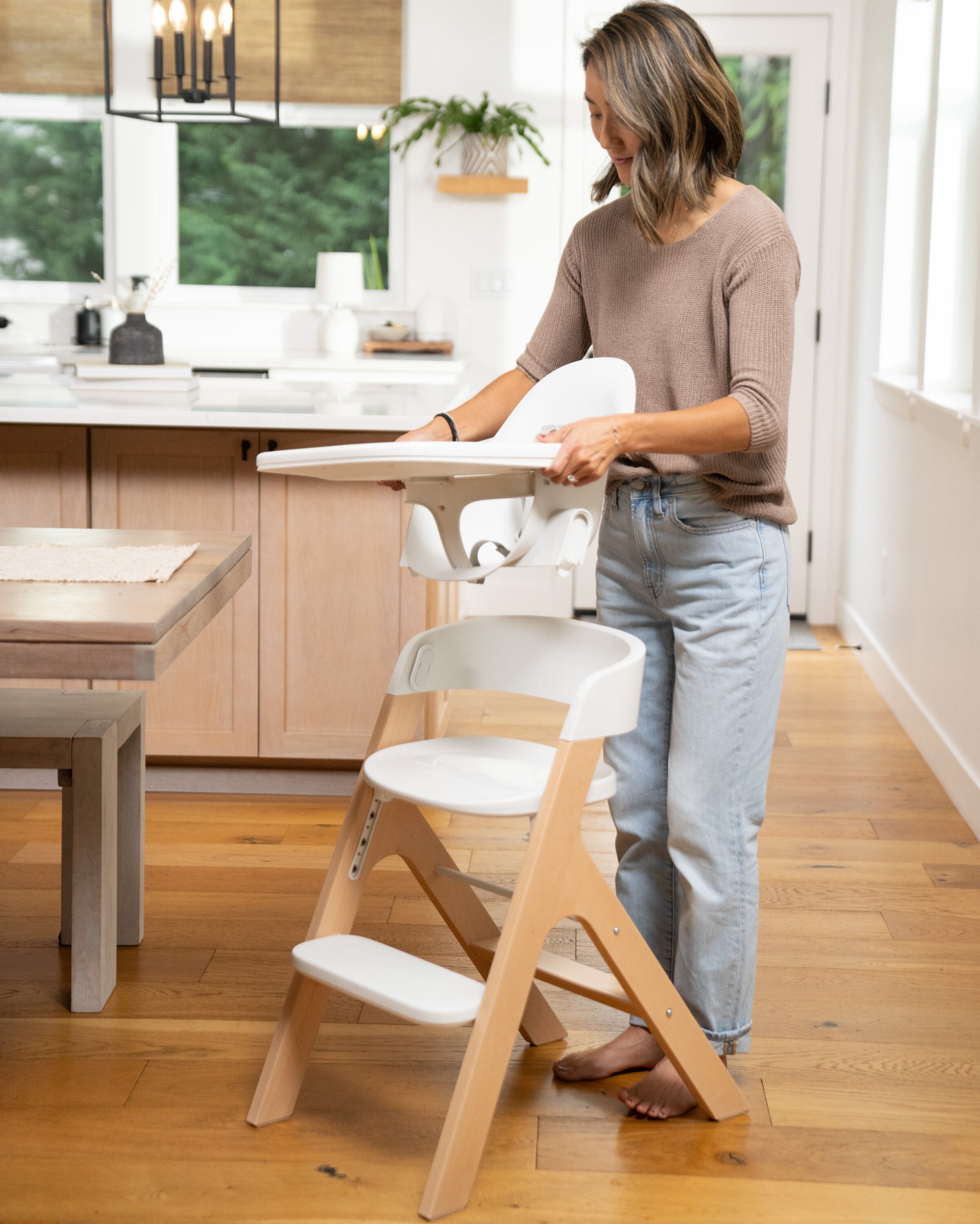 mom transitioning the mockingbird high chair from high chair mode to child mode