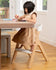 little girl sitting in child mode of the mockingbird high chair eating an apple and reading