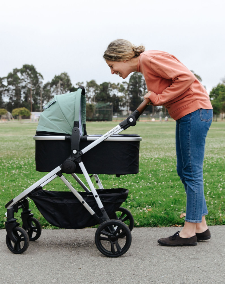 mom looking into her mockingbird bassinet while out on a stroll