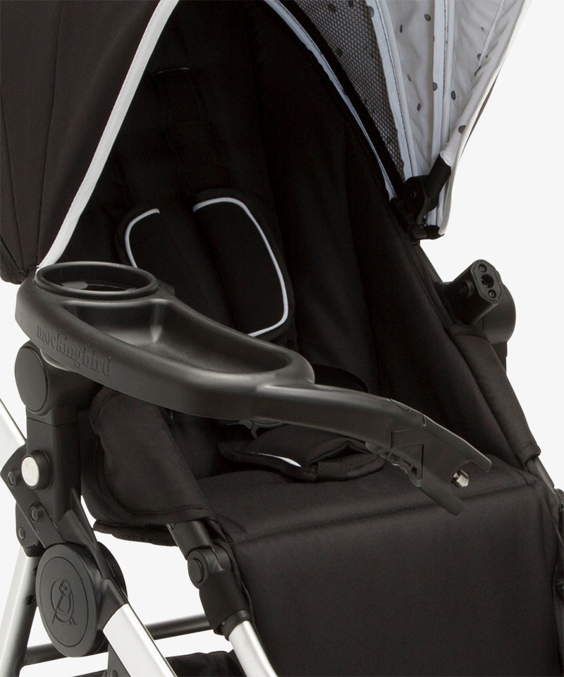 Close-up of an empty black and grey Mockingbird Snack Tray baby stroller showing the cup holder and adjustable handle.