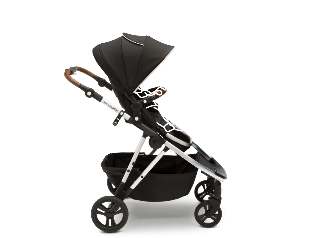 A modern black baby stroller with a large canopy and a lower storage basket, displayed on a white background.