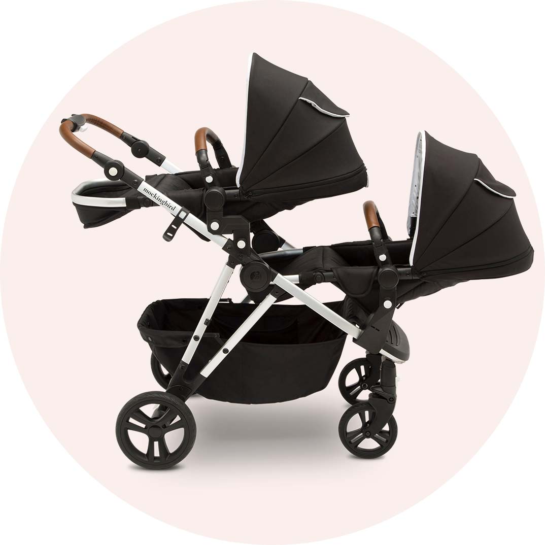 Modern double baby stroller with adjustable seats and canopies on a pink background.