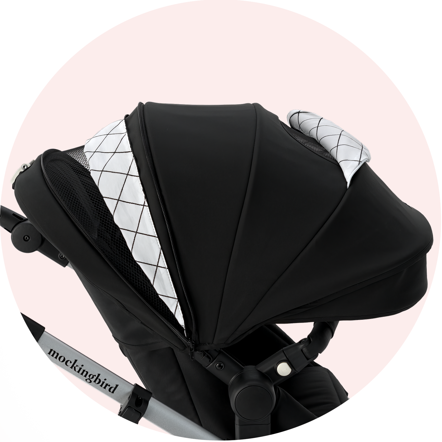 Black and grey baby stroller from mockingbird brand with a hood, extended canopy, and visible geometric pattern on the inner lining, set against a pale pink background.