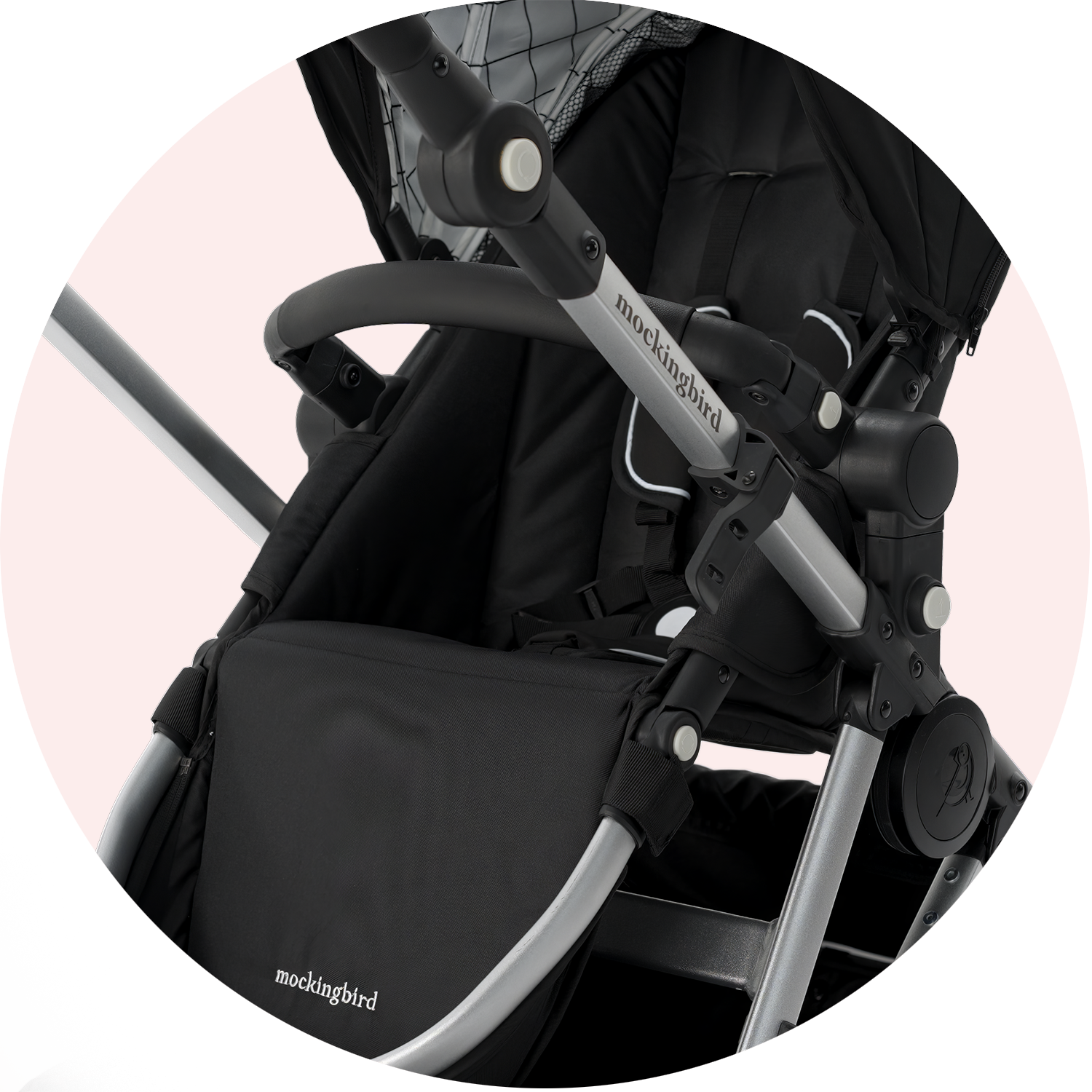 Close-up view of a black mockingbird stroller with visible brand logo, focusing on its handle and canopy attachment points.