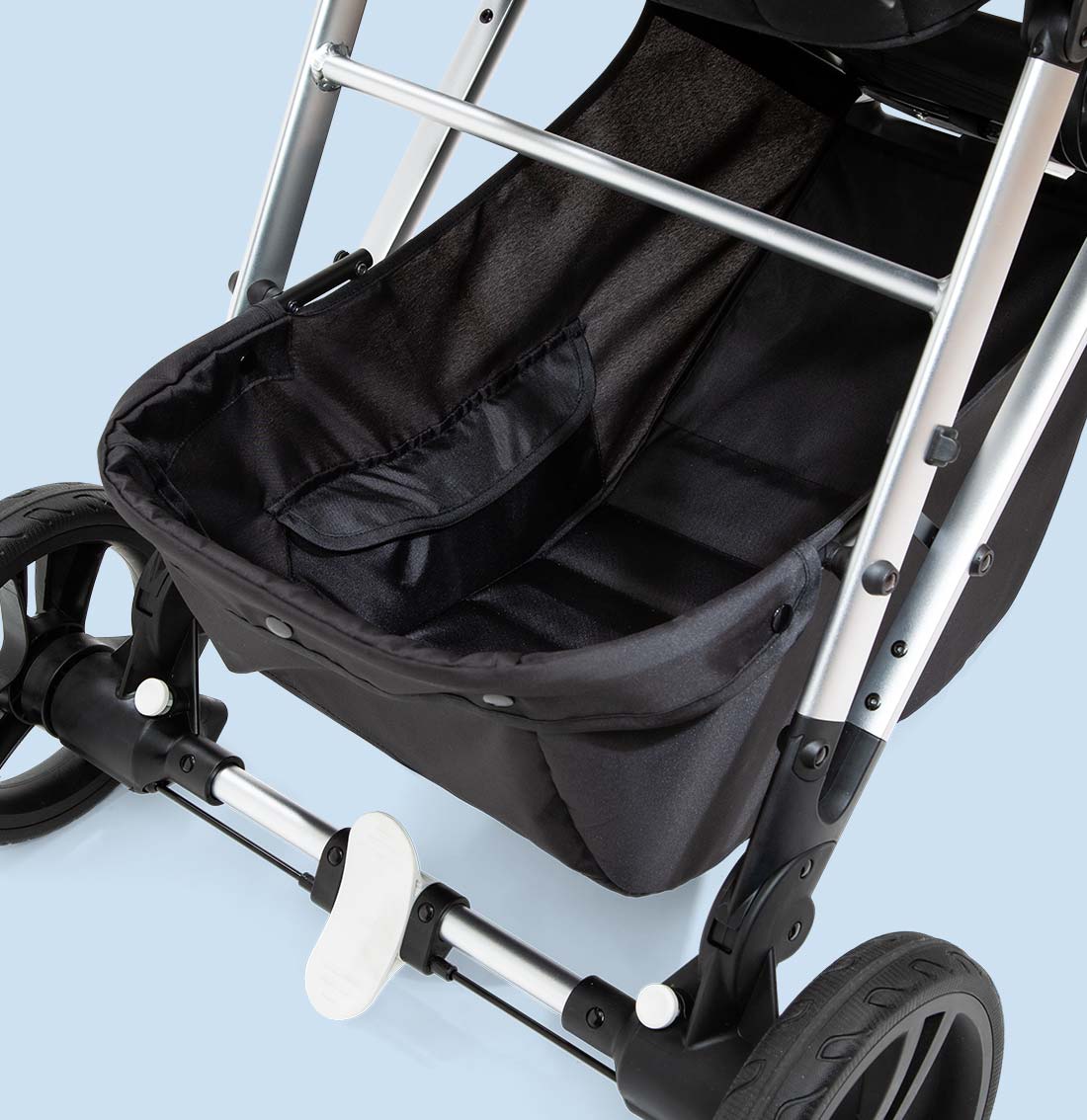 Close-up of a black and silver baby stroller on a light blue background, focusing on the seat and front wheels.
