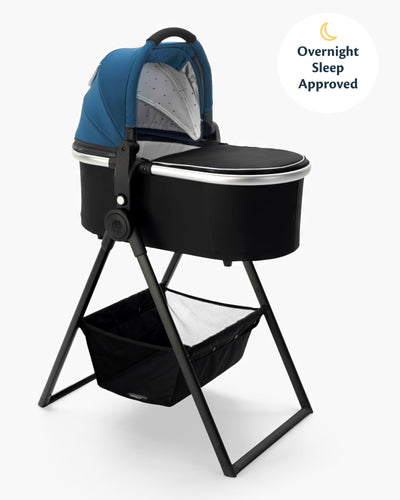 A modern baby bassinet with a blue canopy on a mockingbird-prod bassinet stand, featuring a storage basket underneath and labeled as "overnight sleep approved. #color_sea