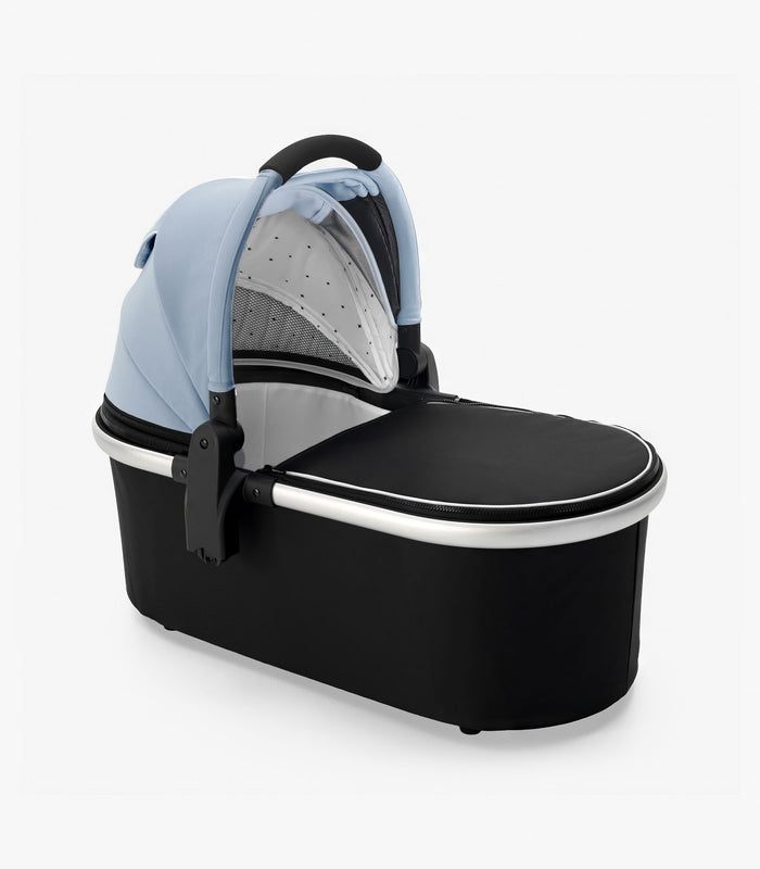 A modern mockingbird-prod bassinet with a light blue canopy, black base, and handle, isolated on a white background. #color_sky