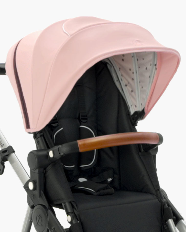 Modern mockingbird-prod stroller with an Extra Stroller Canopy 2.0 in pink, black seat, and a wooden handlebar, isolated on a white background. #color_bloom