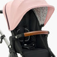 Close-up of a modern mockingbird-prod Extra Stroller Canopy 2.0 featuring a pink canopy, black seat, and a brown handle. #color_bloom