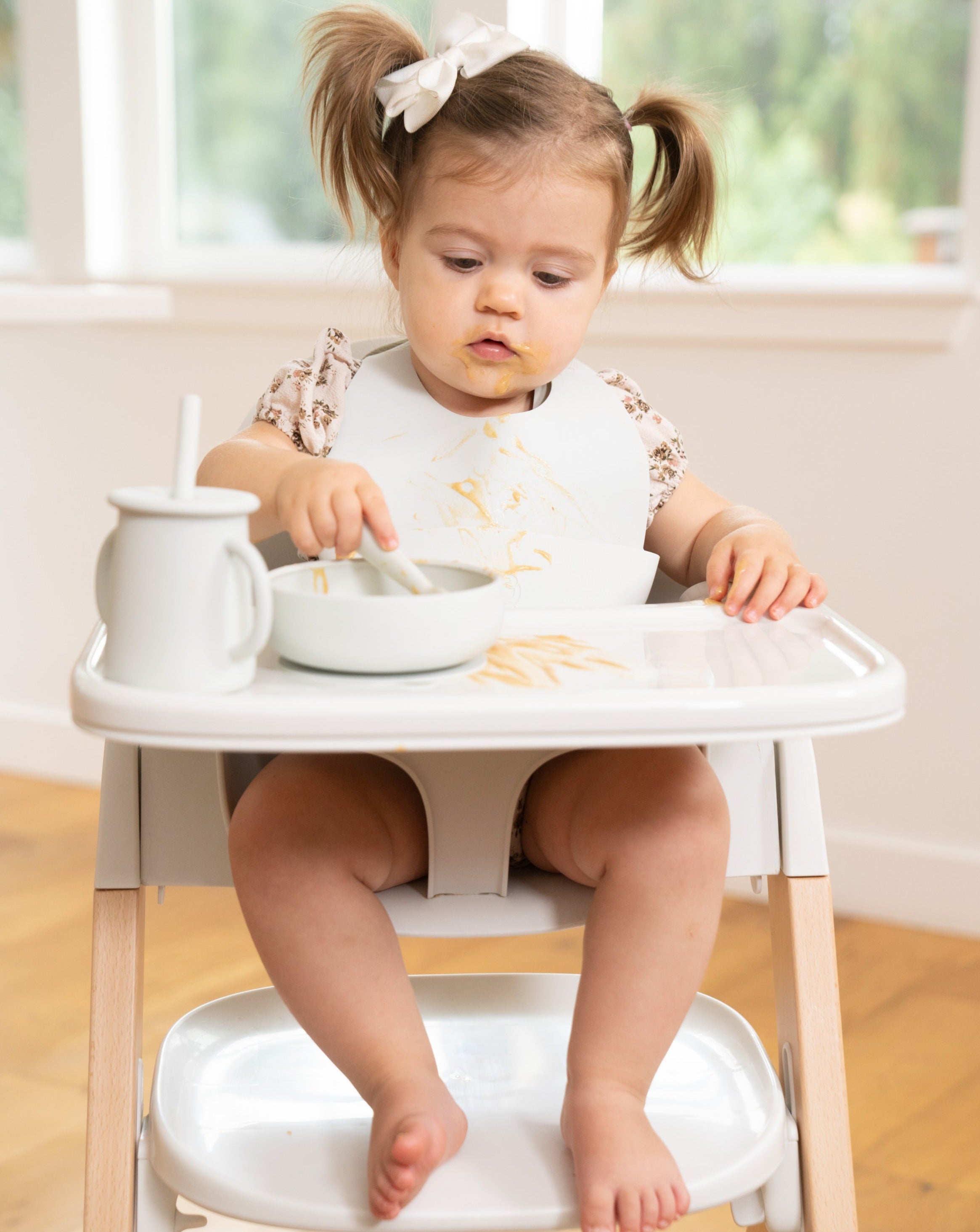 toddler girl eating using light grey mockingbird dishware set for early eaters