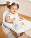 small child eating while sitting in mockingbird high chair in kitchen area