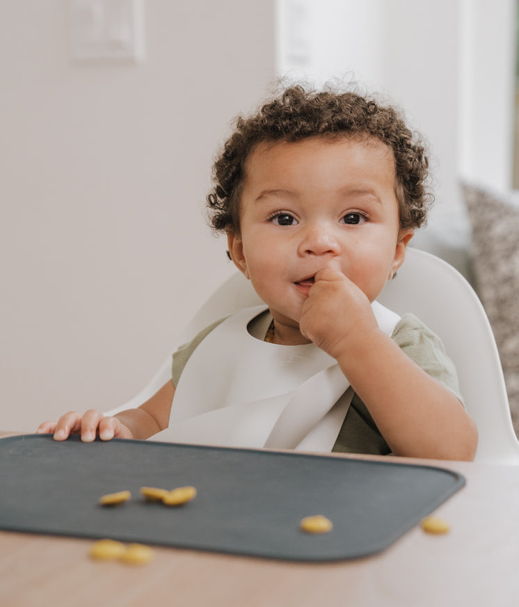 small child with dark curly hair eating a snack