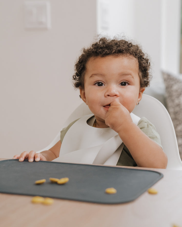 small child with dark curly hair eating a snack