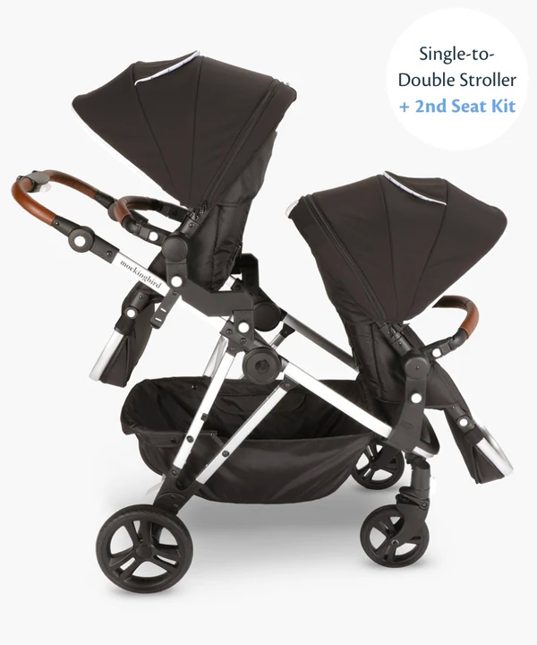 Double stroller with two seats, black fabric, and leather handles, displayed against a white background.