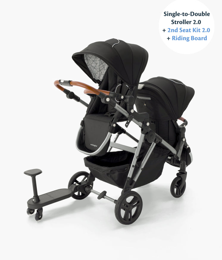 A modern single-to-double stroller with a second seat kit, featuring a sleek black design with a wooden handlebar and a small attached riding board.