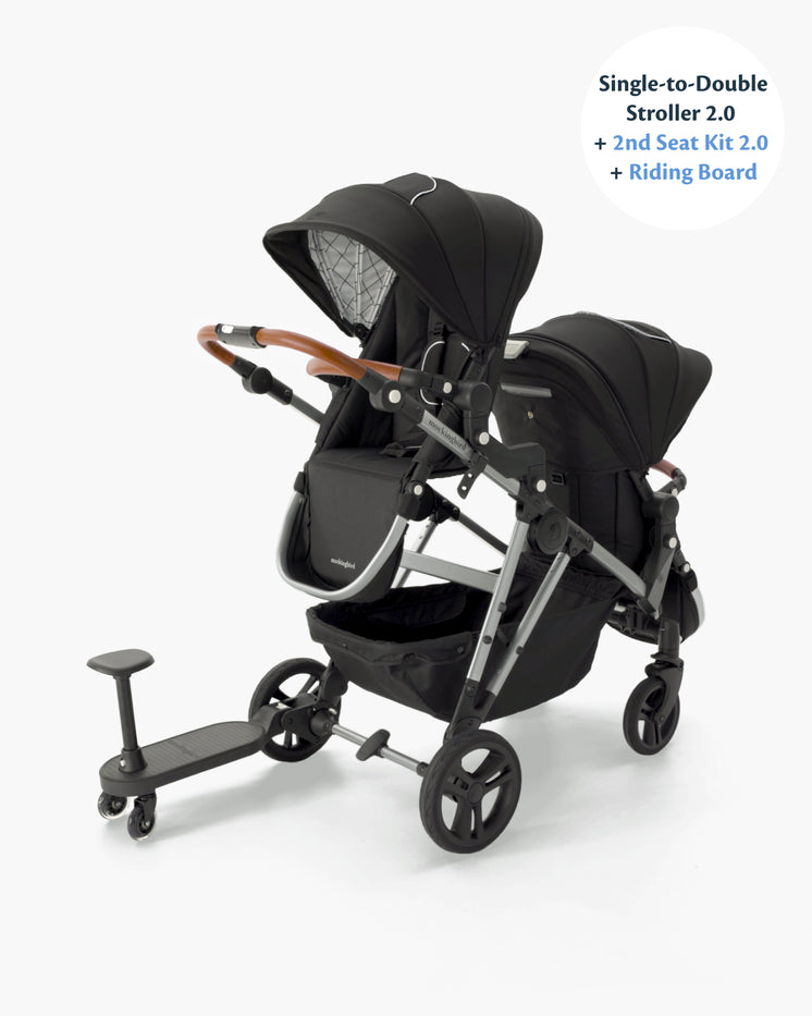 A modern single-to-double stroller with a second seat kit, featuring a sleek black design with a wooden handlebar and a small attached riding board.