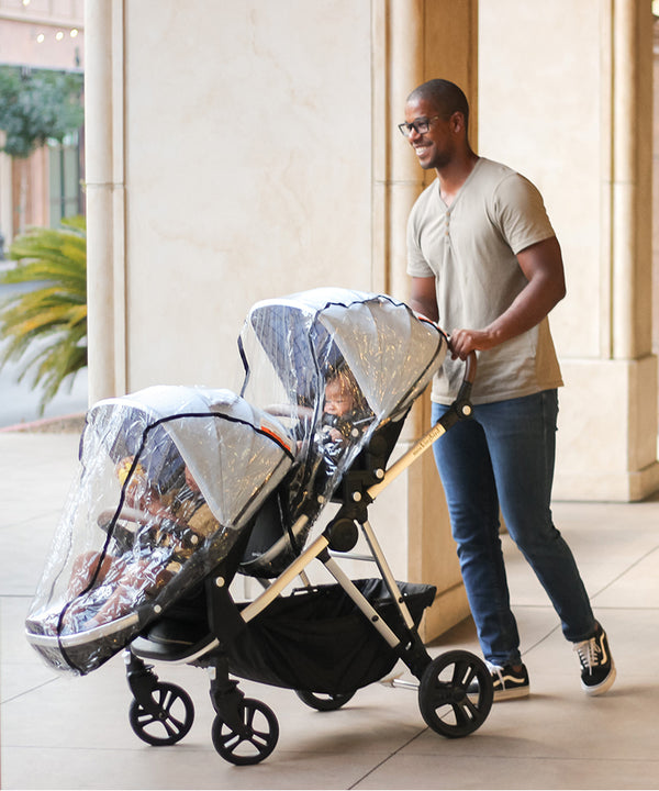 Father pushing a Mockingbird Single-to-Double Stroller with two Rain Covers