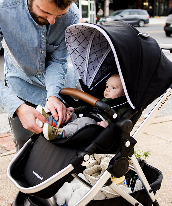 Dad buckling his son into a Mockingbird Stroller